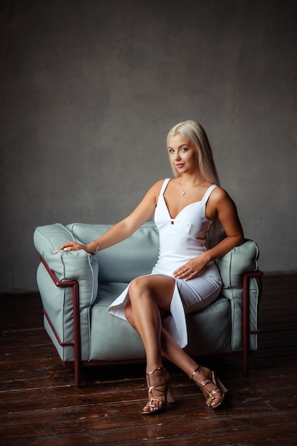 Retrato de uma linda loira em um vestido branco no interior do estúdio