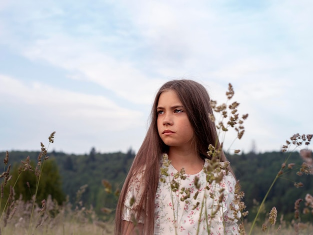 Retrato de uma linda menina com cabelos longos em um campo