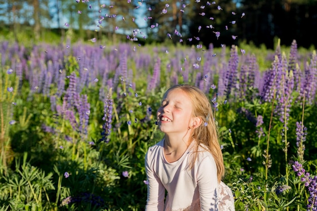 Retrato de uma linda menina de sete anos com tremoços de flores em flor no campo de flores roxas Criança joga flores conceito de natureza Provence Infância Férias de verão