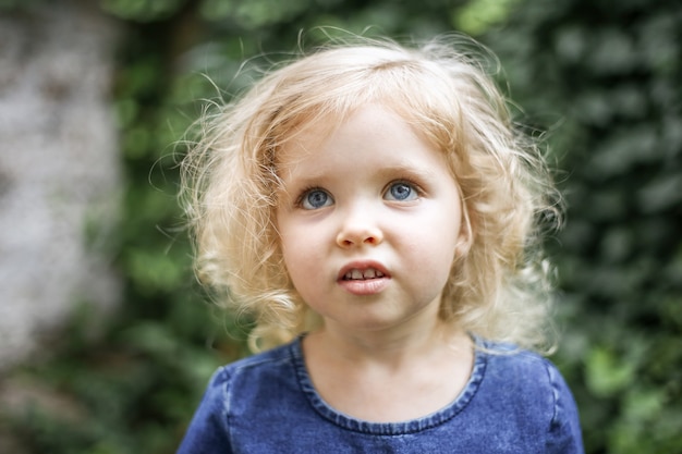 Retrato de uma linda menina europeia com cabelo loiro encaracolado e olhos azuis