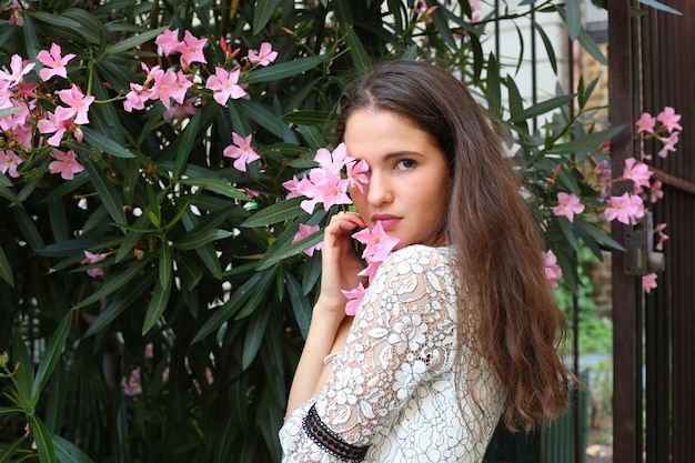 Retrato de uma linda menina morena cobrindo os olhos com uma flor rosa