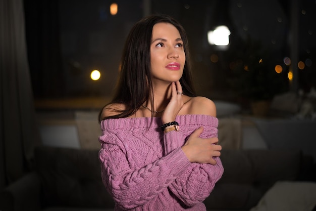 Retrato de uma linda menina morena com uma blusa rosa com guirlandas desfocadas