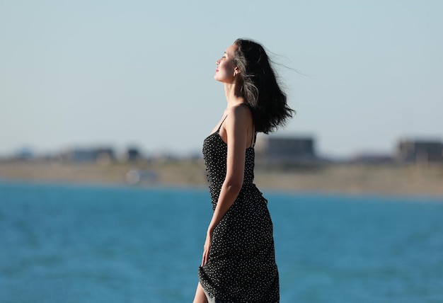 Retrato de uma linda menina morena em um vestido preto no fundo do mar