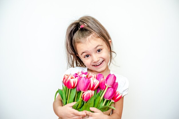 Retrato de uma linda menina sorridente com tulipas da primavera em um fundo branco.