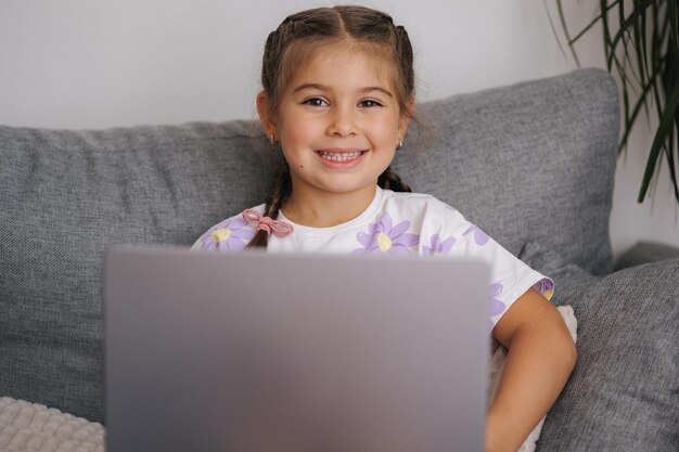 Retrato de uma linda menina usando um dispositivo inteligente menina de cinco anos aberta e usar laptop