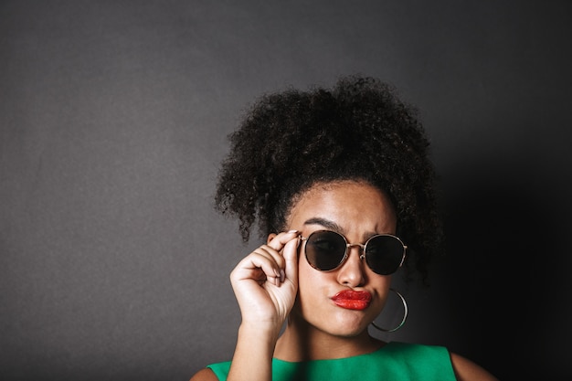 Foto retrato de uma linda mulher afro-americana de óculos escuros isolado sobre o espaço negro.