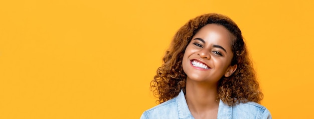 Retrato de uma linda mulher afro-americana sorrindo isolada em fundo de faixa amarela com espaço de cópia