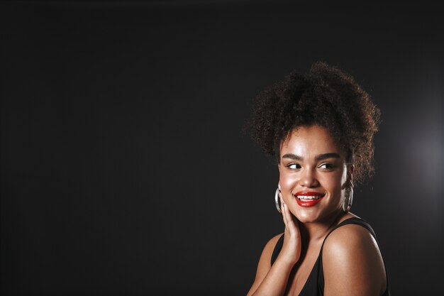 Retrato de uma linda mulher afro-americana usando maquiagem em pé isolado no espaço negro