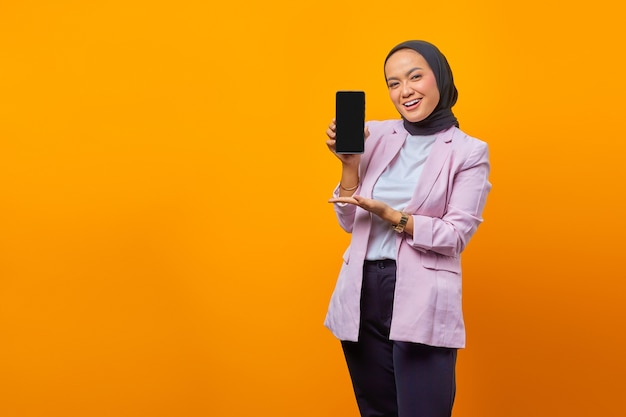 Retrato de uma linda mulher asiática alegre mostrando uma tela em branco no smartphone