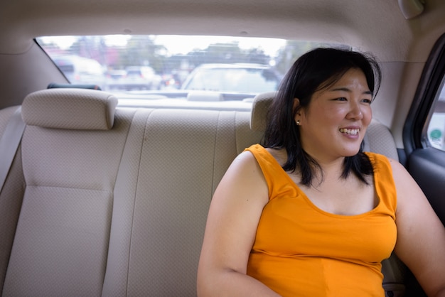 Retrato de uma linda mulher asiática com excesso de peso dentro de um carro pela cidade de Bangkok, Tailândia