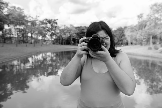 Retrato de uma linda mulher asiática com excesso de peso relaxando no parque da cidade em preto e branco