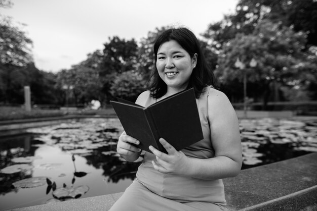 Retrato de uma linda mulher asiática com excesso de peso relaxando no parque da cidade em preto e branco