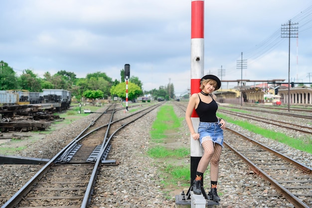 Retrato de uma linda mulher asiática com um novo visual com cabelos curtos no trem antigoVestido preto com saia jeans ao ar livre tailândia