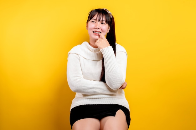 Retrato de uma linda mulher asiática com um rosto sorridente. Mulher asiática, vestindo roupas casuais. Estilo de vida tailandês. Sorriso brilhante de garota fofa em um fundo amarelo