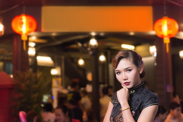 Retrato de uma linda mulher asiática de vestido preto na cena noturna de fundo de taverna embaçadaSua maquiagem e estilo de cabelo para sessão de fotos conceito de filme chinês