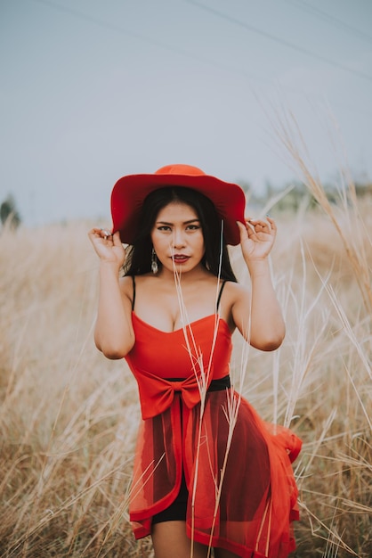 Retrato de uma linda mulher asiática de vestido vermelho com chapéu vermelho no campo, mulher triste, desgosto, estilo vintage