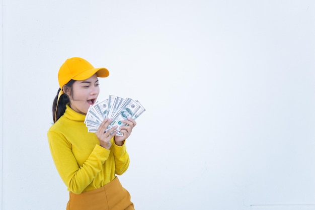 Retrato de uma linda mulher asiática em panos amarelos na parede branca suja Garota descolada usa chapéu amarelo tira uma fotoO povo da Tailândia tem muito dinheiro na mão
