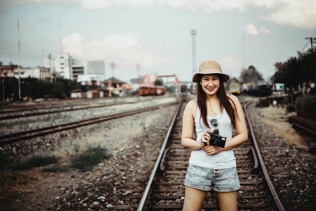 Retrato de uma linda mulher asiática em uma camiseta branca com câmera na mão no estilo vintage ferroviário