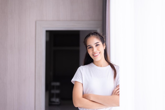 Retrato de uma linda mulher asiática feliz sorrindo e olhando para a câmera enquanto está em casa