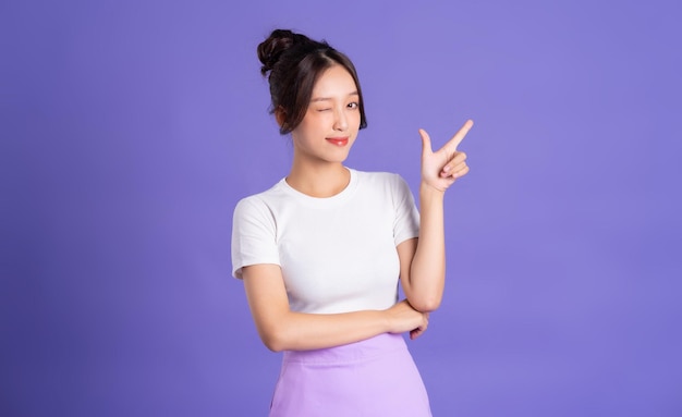 Retrato de uma linda mulher asiática posando em um fundo roxo