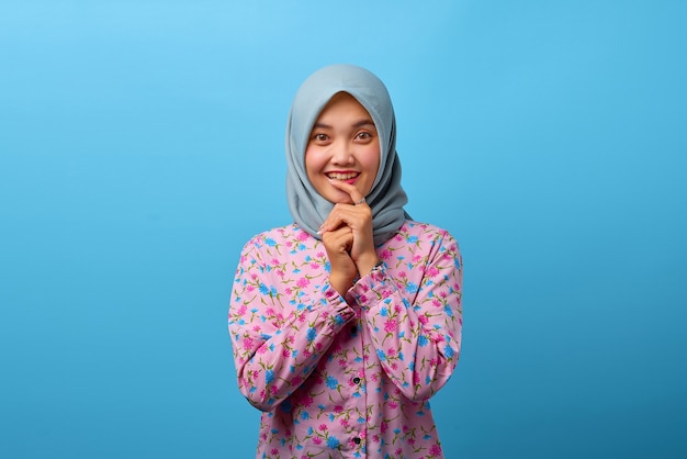 Retrato de uma linda mulher asiática se sentindo feliz em um fundo azul