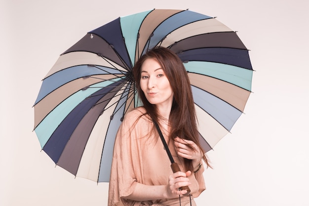 Retrato de uma linda mulher asiática sob o guarda-chuva listrado na parede branca