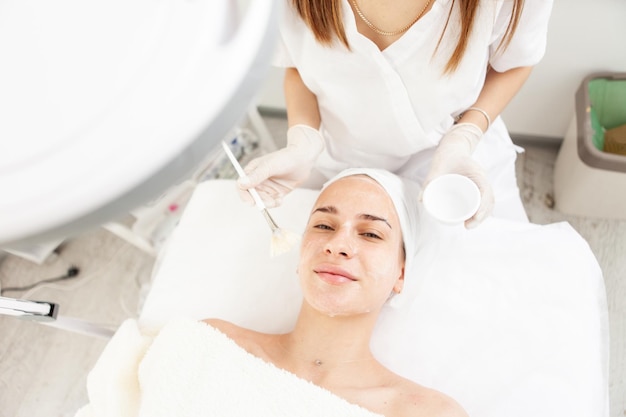 Retrato de uma linda mulher caucasiana deitada em um sofá durante um procedimento por uma esteticista Cuidados com a pele facial