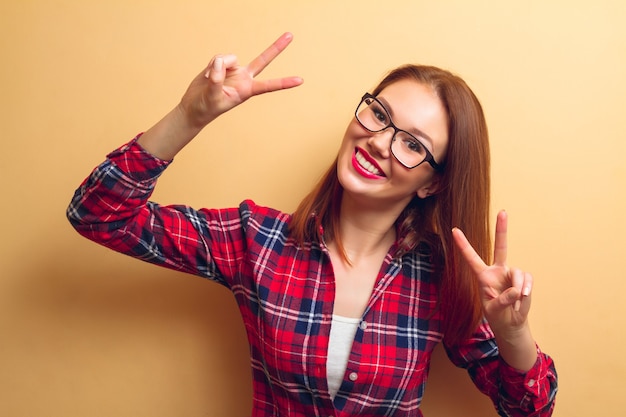 Retrato de uma linda mulher com batom vermelho em uma camisa quadriculada. um símbolo de vitória. instantâneo