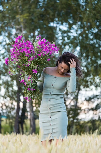 Retrato de uma linda mulher com um buquê de flores caminhando no campo