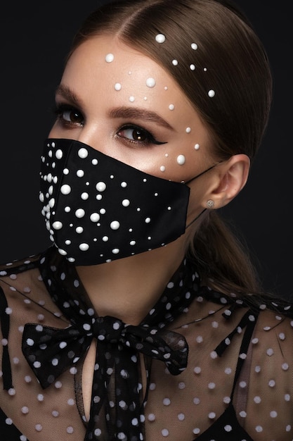 Retrato de uma linda mulher com uma máscara preta com pérolas e maquiagem clássica Modo de máscara durante a pandemia de covid