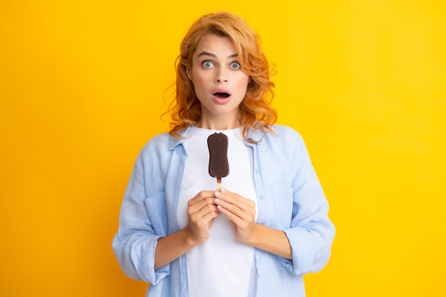 Retrato de uma linda mulher comendo sorvete em fundo amarelo alaranjado Garota comendo gelo de picolé