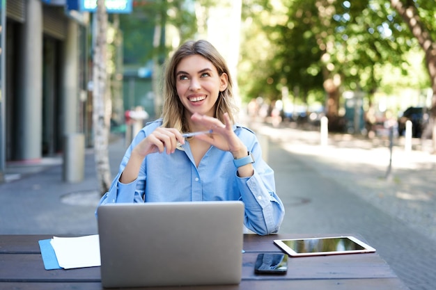 Retrato de uma linda mulher corporativa sentada com laptop ao ar livre conversando por vídeo no laptop falando