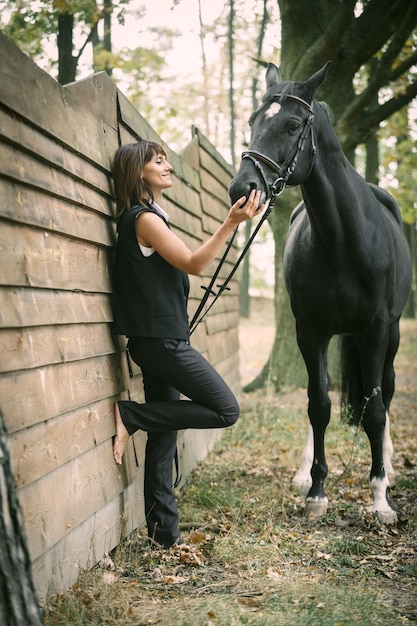 Retrato de uma linda mulher de cabelo castanho vestida de cavalo preto e preto ao ar livre Foto do dia