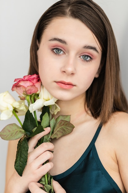 Retrato de uma linda mulher de cabelos escuros com flores. Foto de moda, menina bonita com rosa rosa