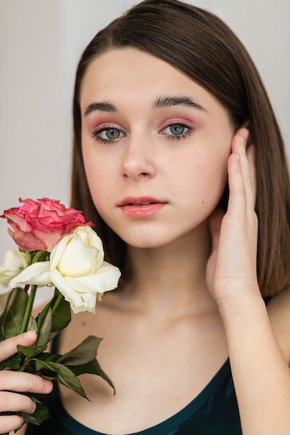 Retrato de uma linda mulher de cabelos escuros com flores. Foto de moda, menina bonita com rosa rosa