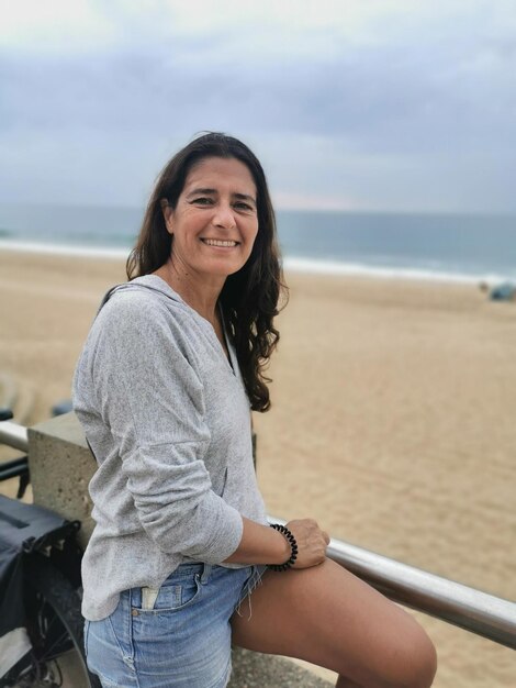 Foto retrato de uma linda mulher de meia idade posando alegremente na praia