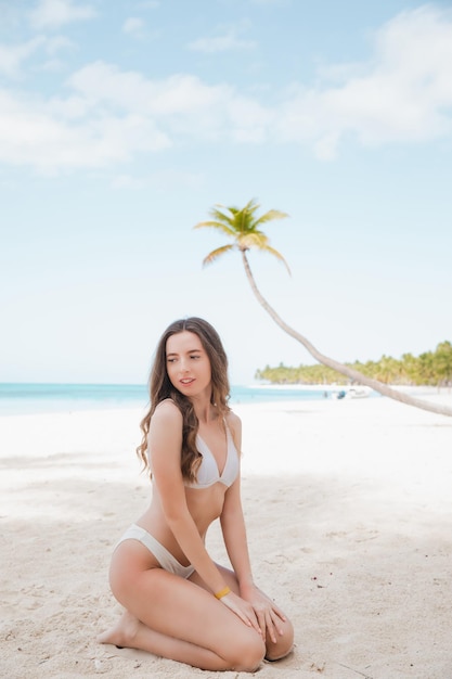 Retrato de uma linda mulher de moda esportiva em biquíni branco posando no verão perto do mar