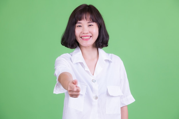 Retrato de uma linda mulher de negócios asiática com cabelo curto contra chroma key ou parede verde