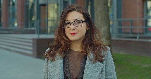 Retrato de uma linda mulher de negócios com óculos de pé ao ar livre e olhando para a câmera.