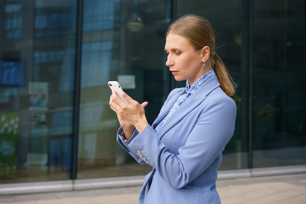 Retrato de uma linda mulher de negócios com uma jaqueta azul, falando ao telefone no contexto de um prédio de escritórios