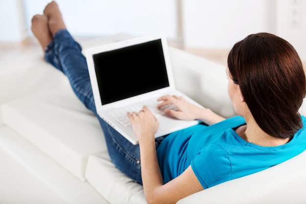 Retrato de uma linda mulher de negócios sentada no sofá e usando o laptop enquanto olha para a câmera