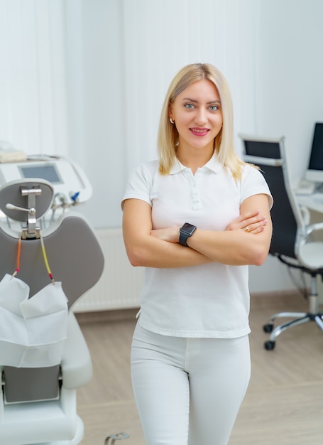 Retrato de uma linda mulher dentista olhando para a câmera em um consultório dentista. Estomatologista em uniforme branco.