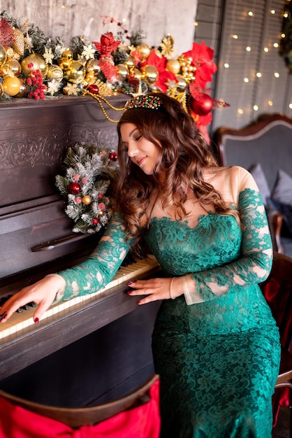 Retrato de uma linda mulher elegante no fundo das decorações de Ano Novo e Natal Ela está sentada ao piano