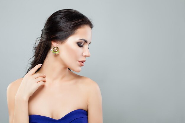 Retrato de uma linda mulher em brincos de joias da moda com gema verde e perfil feminino de diamante