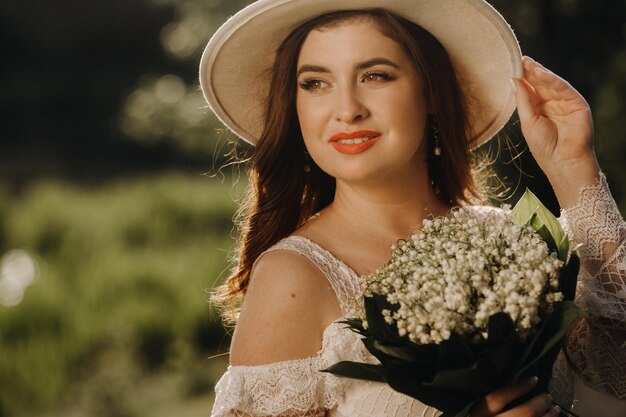 Retrato de uma linda mulher em um vestido branco e um chapéu com lírios do vale Uma garota na natureza Flores da primavera