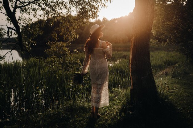 Retrato de uma linda mulher em um vestido branco e um chapéu com lírios do vale Uma garota na natureza Flores da primavera