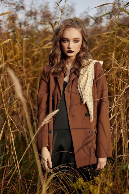 Retrato de uma linda mulher fashion em um bosque de grama de outono