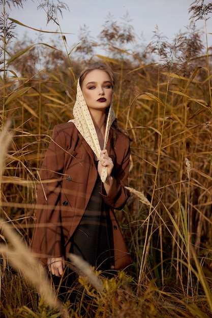 Retrato de uma linda mulher fashion em um bosque de grama de outono