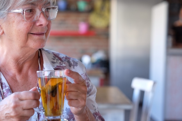 Retrato de uma linda mulher idosa no café, desfrutando de um chá de ervas. Pessoas idosas de cabelos grisalhos