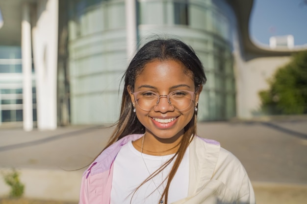 Retrato de uma linda mulher latina sorrindo e olhando para a câmera ao ar livre no campus estudantil